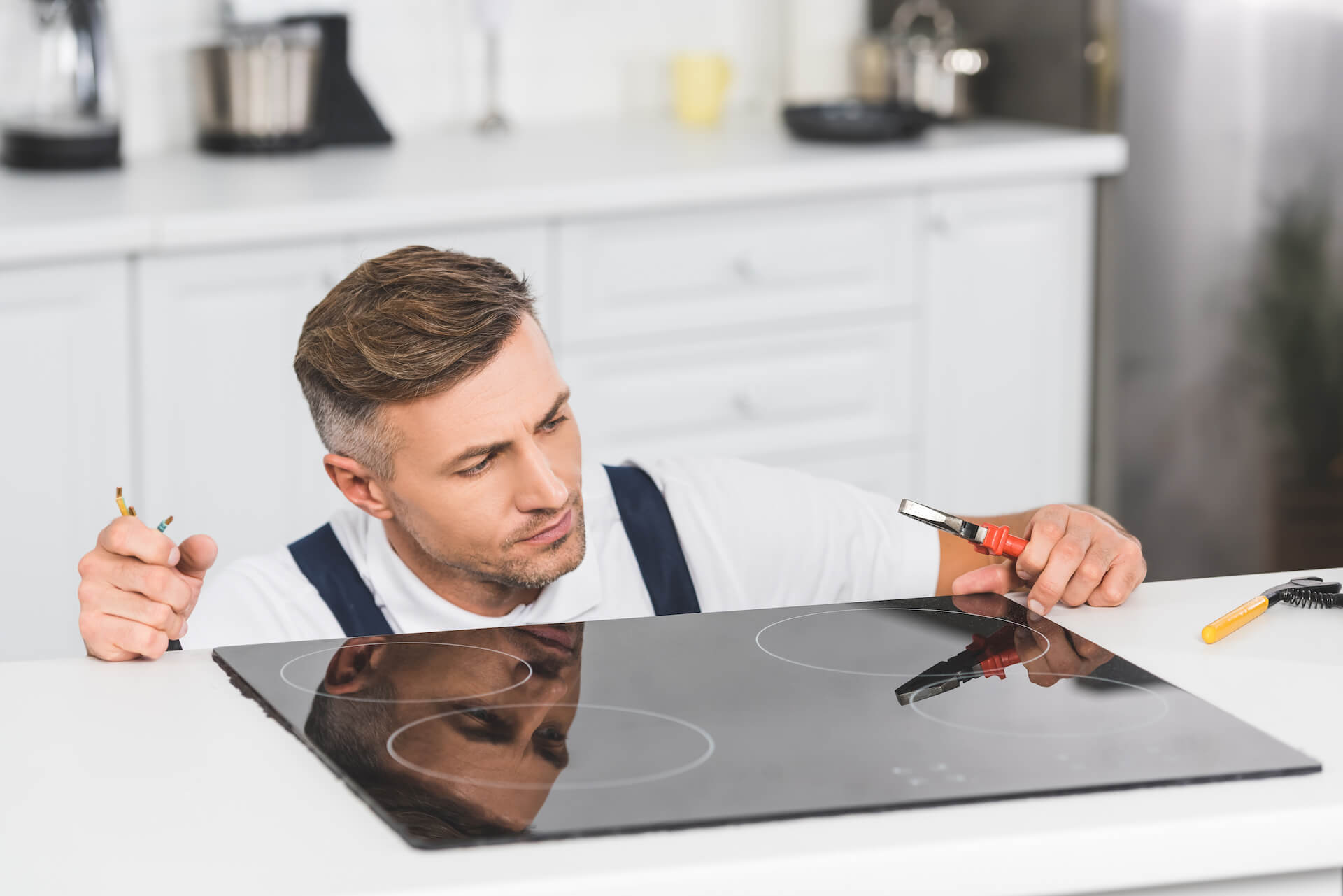 Photo of a repairman inspecting a stove | Featured image for [Stovetop Electrician] | Service Page for Latched Electrical Solutions.